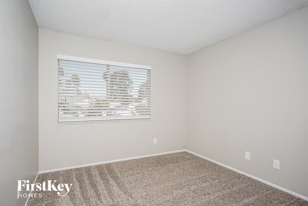 a spacious room with carpet and a window
