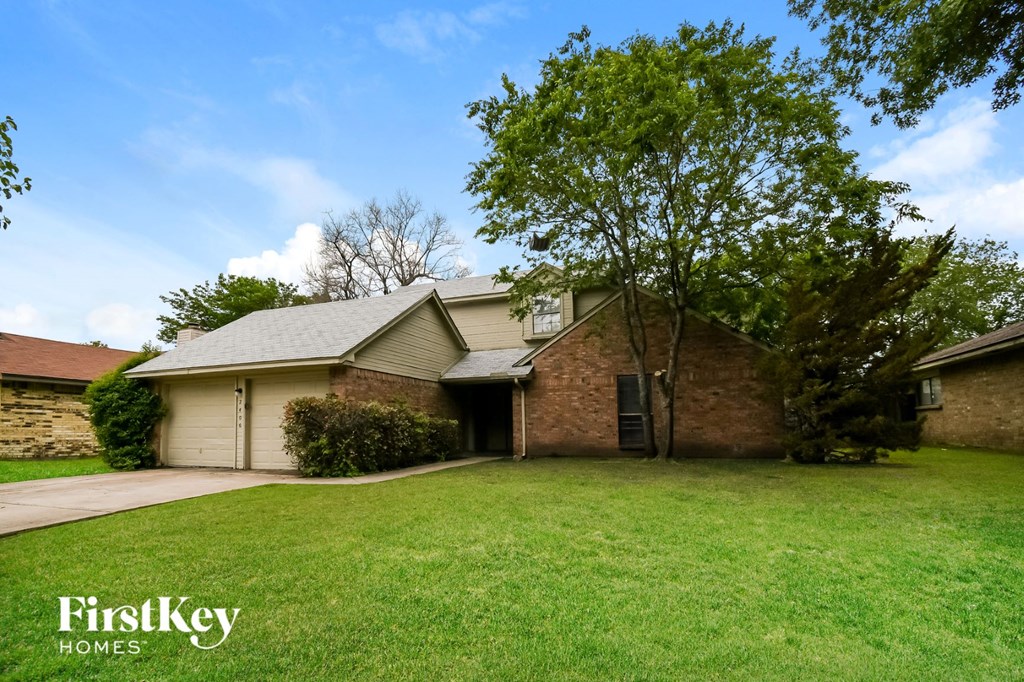 a brick house with a lawn and a tree