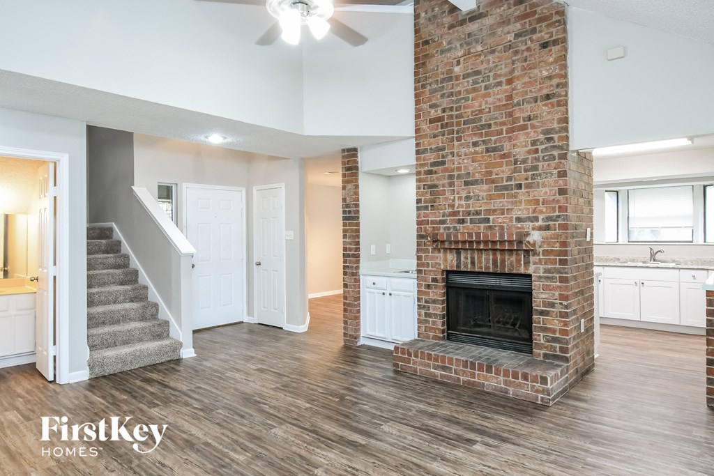 a living room with a brick fireplace and a staircase