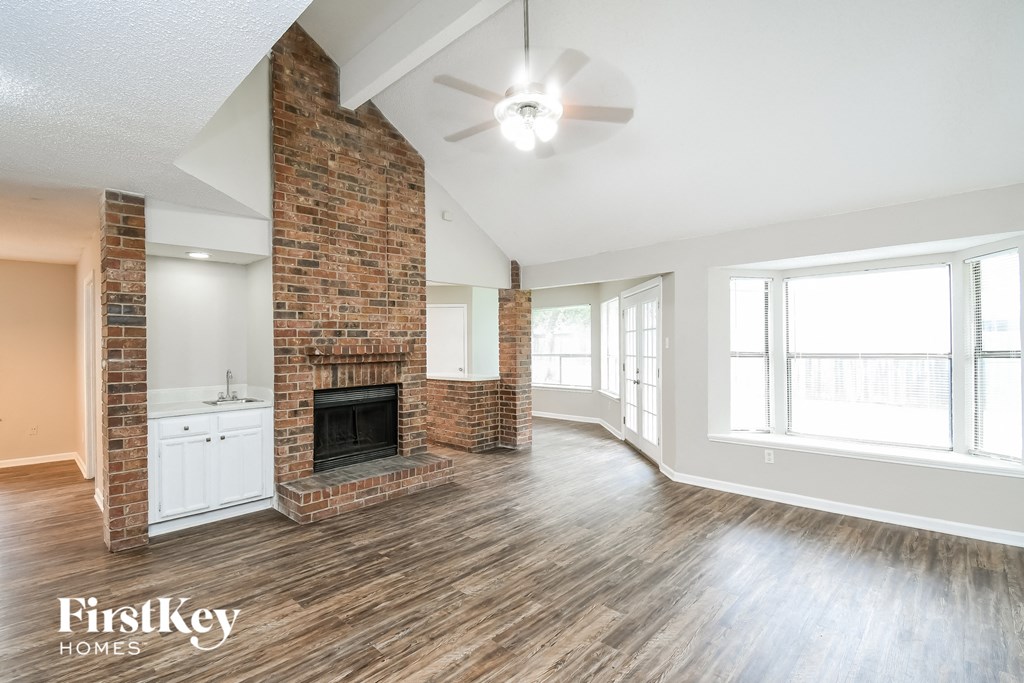 a living room with a brick fireplace and a ceiling fan