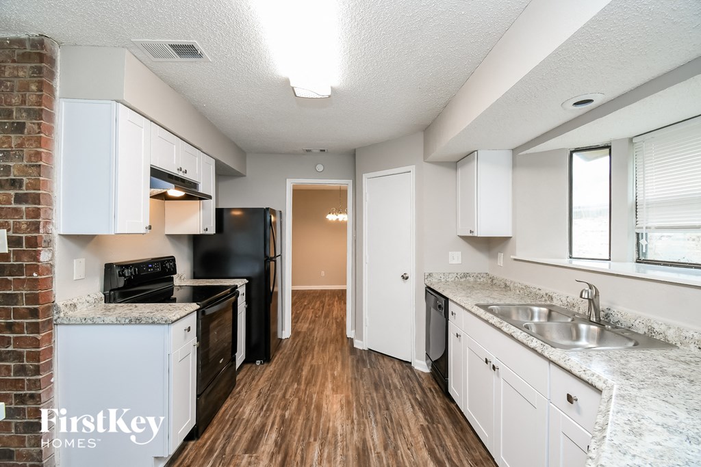 a kitchen with white cabinets and black appliances and a wood floor