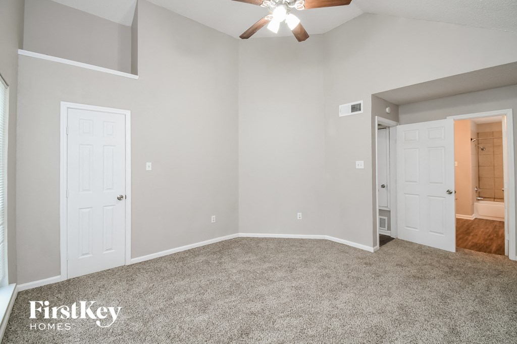 the living room of an empty home with white doors and a ceiling fan