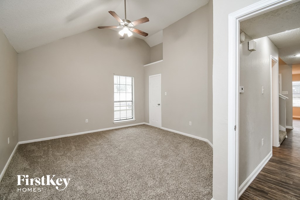 an empty living room with a ceiling fan and a window