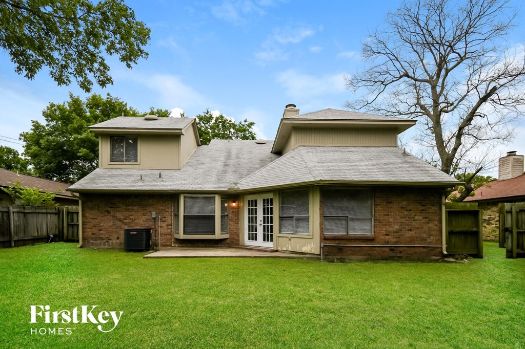 front view of a brick house with a yard and a tree