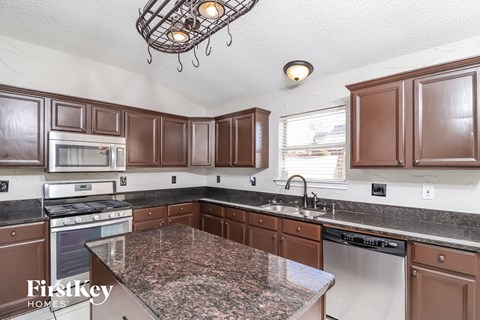 A kitchen with brown cabinets and granite countertops.