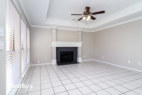 A living room with a fireplace and a ceiling fan.