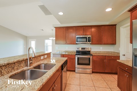 A kitchen with brown cabinets and a granite countertop.