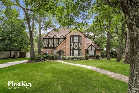 A house with a large lawn and trees in front of it.