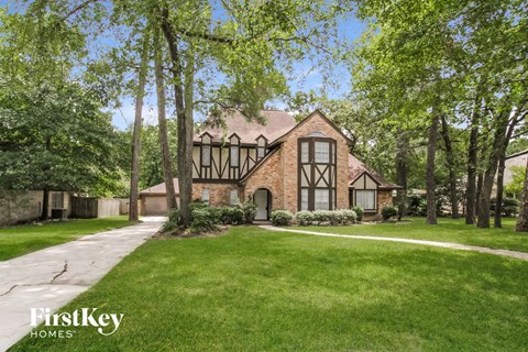 A house with a large lawn and trees in front of it.