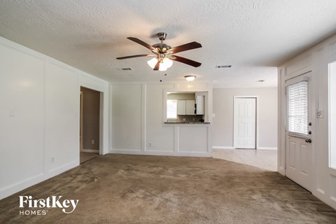 A spacious room with a carpeted floor and a ceiling fan.