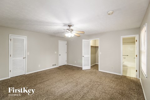 a spacious living room with carpet and a ceiling fan