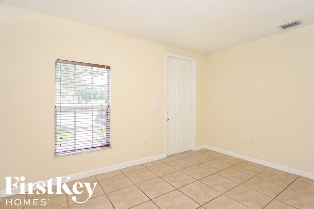 an empty living room with a window and tiled floors