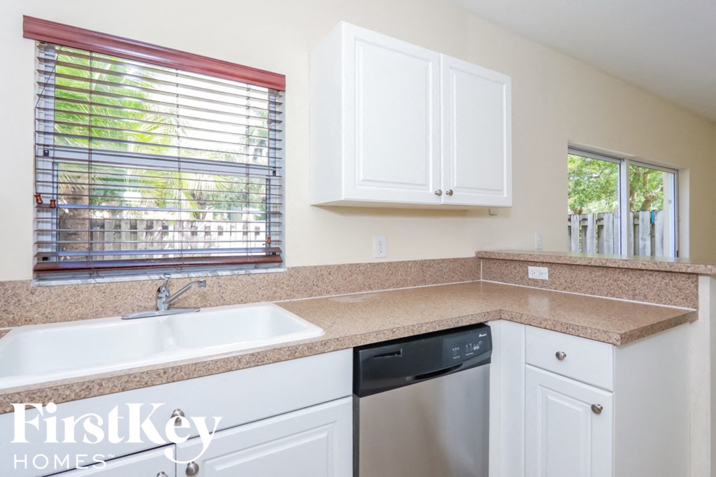 a kitchen with white cabinets and a sink and a window