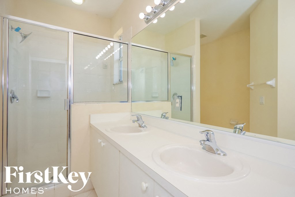 a white bathroom with two sinks and a shower