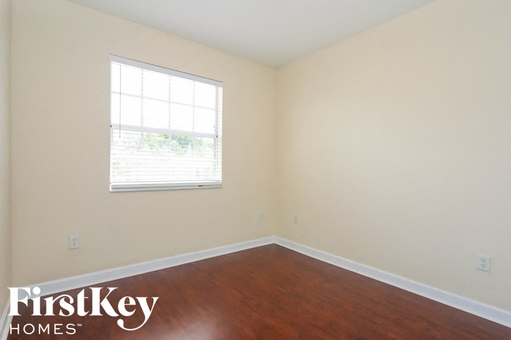 a bedroom with wood floors and a window