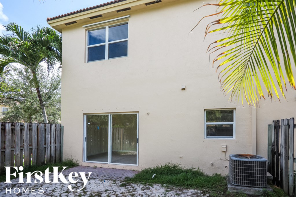 the outside of a house with a fan and palm tree