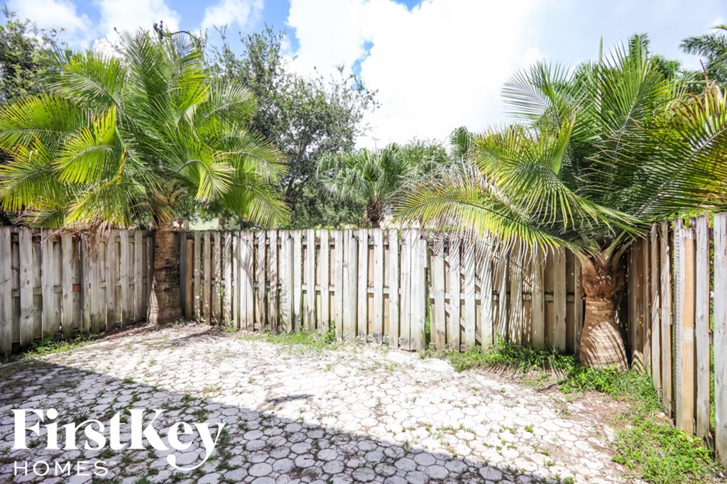 a backyard with a fence and palm trees