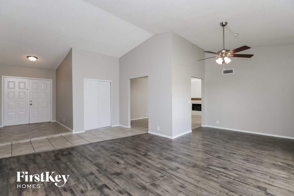 A spacious room with a ceiling fan and wooden flooring.