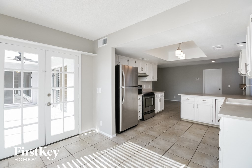 A kitchen with a refrigerator, sink, and cabinets.
