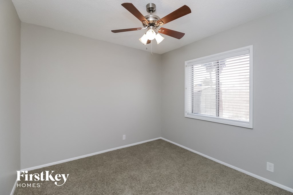 A room with a ceiling fan and a window with blinds.