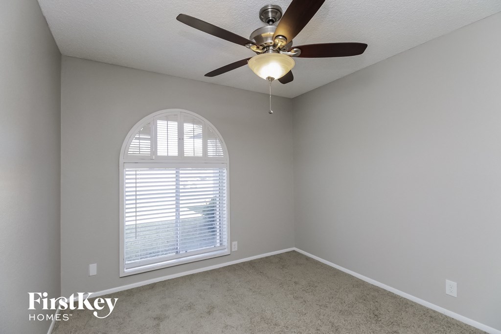 A room with a ceiling fan and a window with blinds.