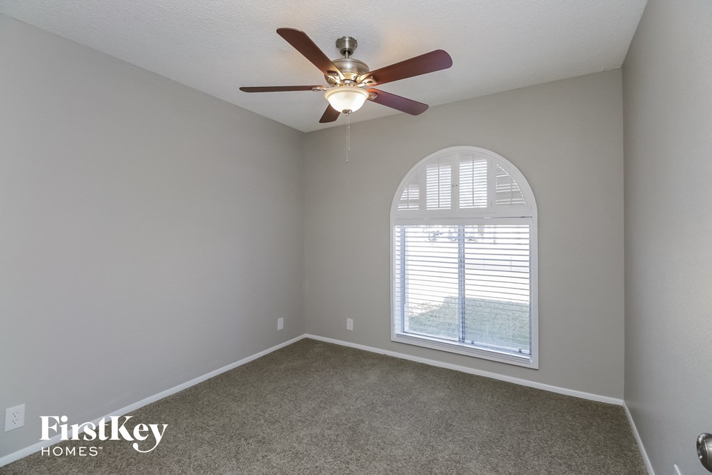 A room with a ceiling fan and a window with blinds.