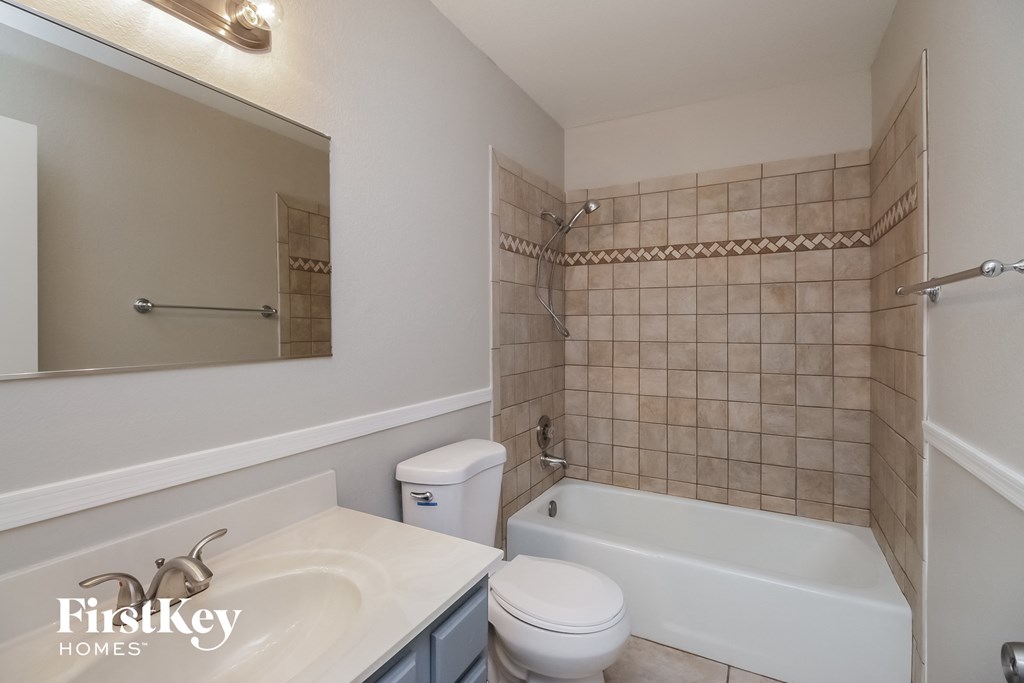 A bathroom with a white tub, sink, and toilet.