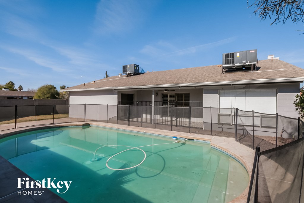 A swimming pool in a backyard with a FirstKey Homes logo.