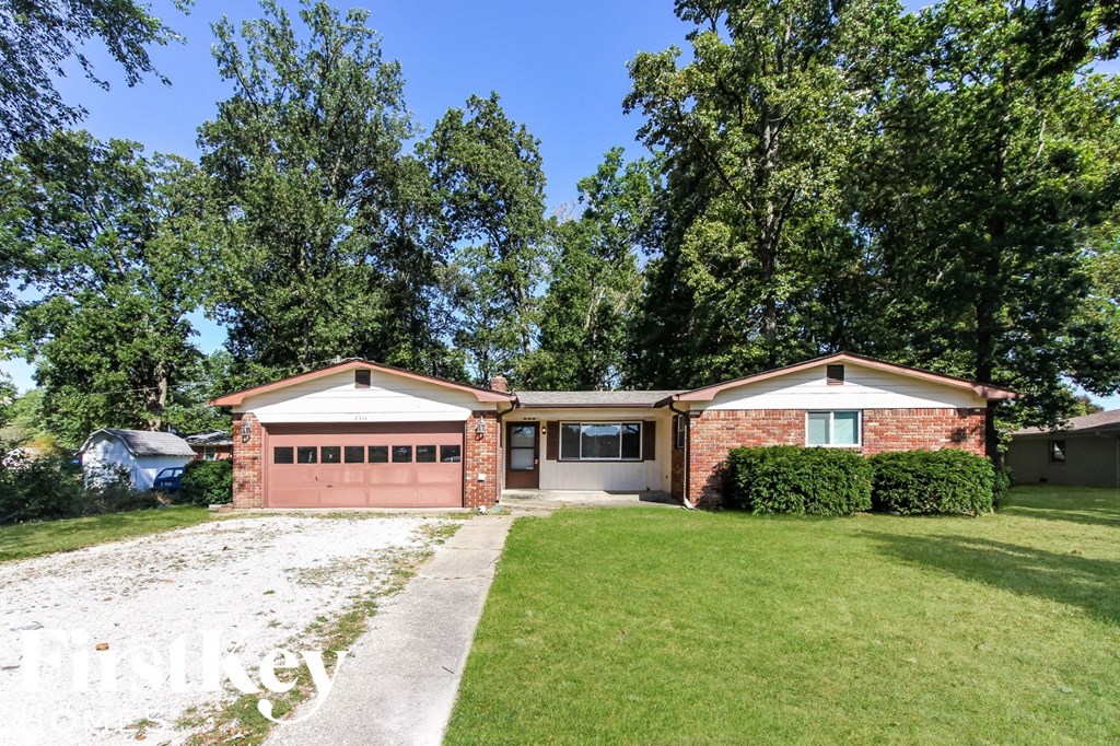a brick house with a lawn and a driveway