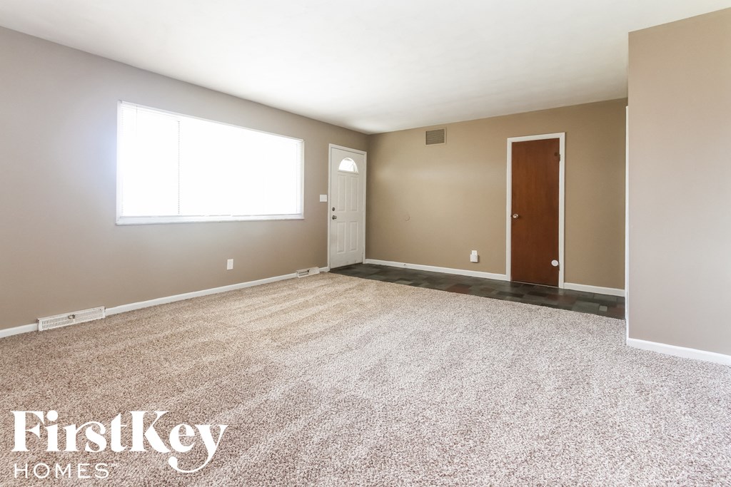a white carpeted room with a white door and a window