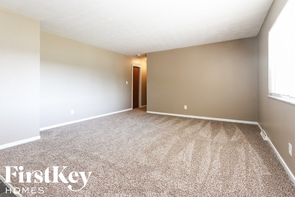 an empty living room with carpet and a window