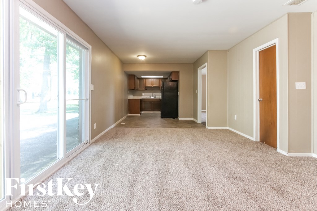 an empty living room and kitchen with large windows