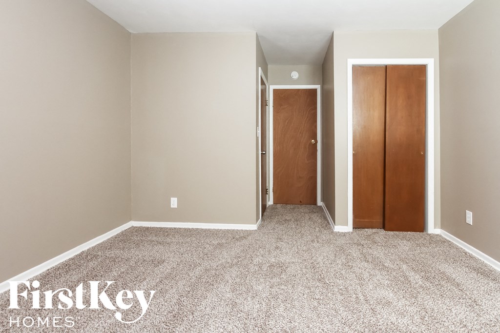 a empty room with carpet and two doors