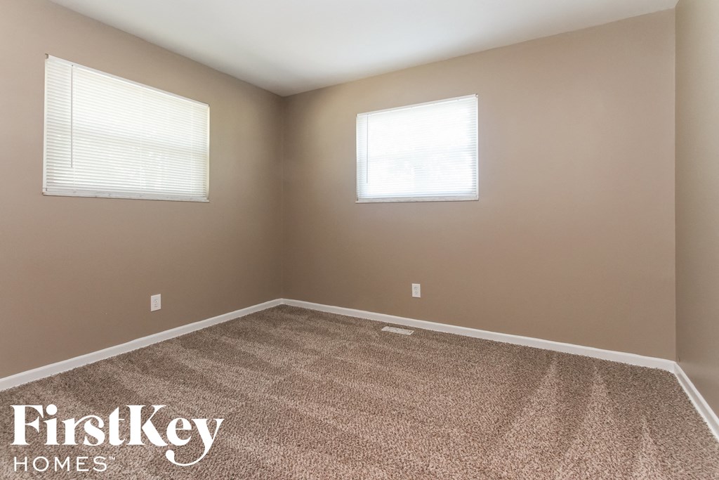 a empty room with two windows and a carpeted floor