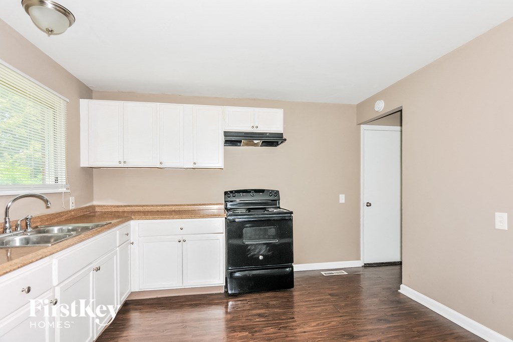 a kitchen with white cabinets and a stove and a sink