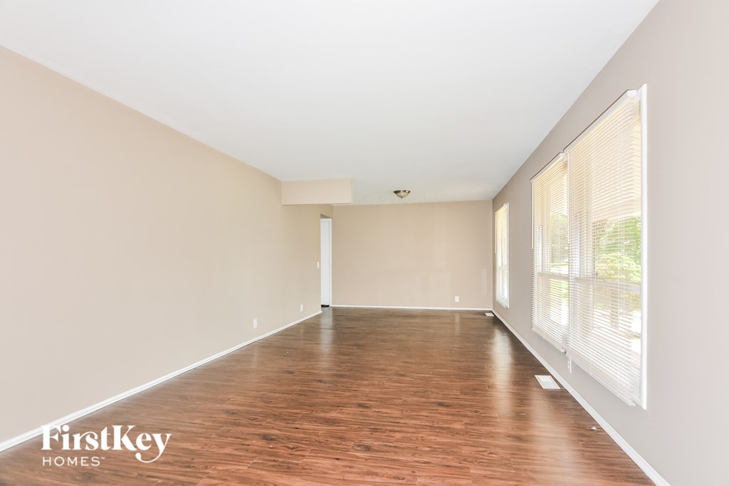 an empty living room with wood flooring and large windows