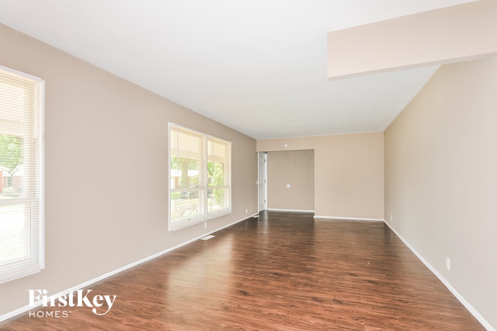 an empty living room with wood floors and a large window