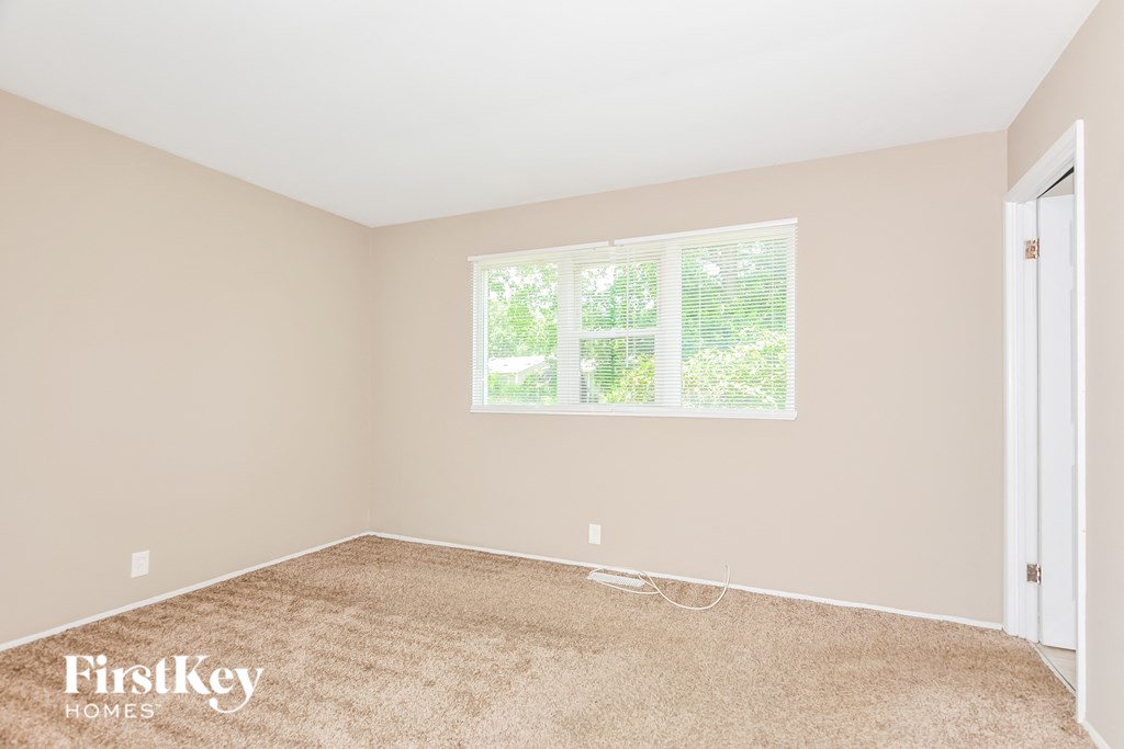 a bedroom with beige carpet and a window