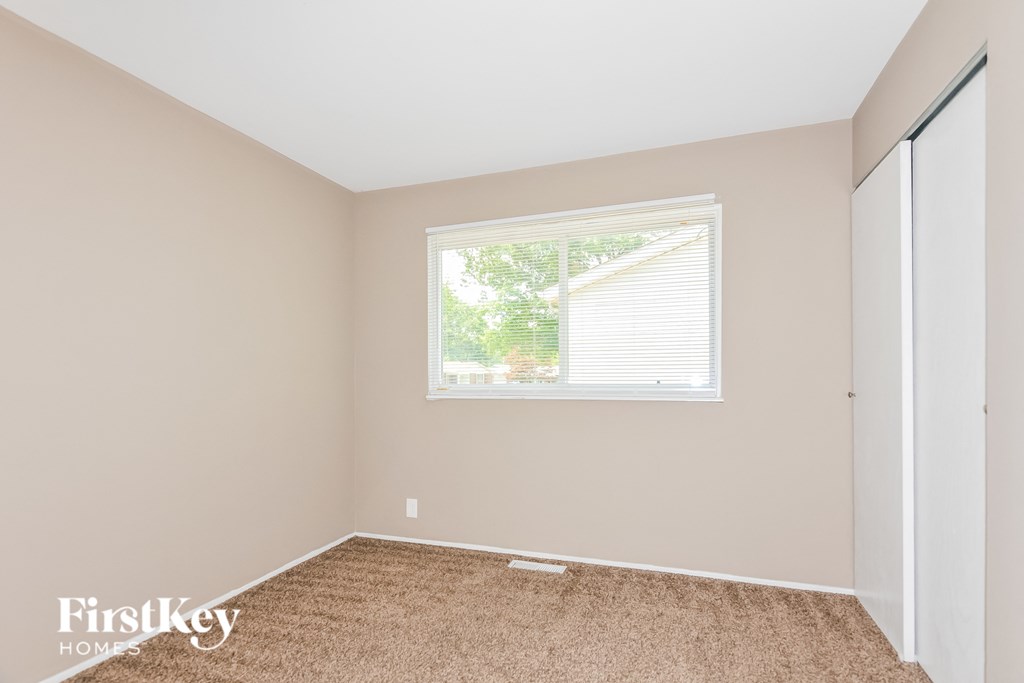 a bedroom with a window and a carpeted floor