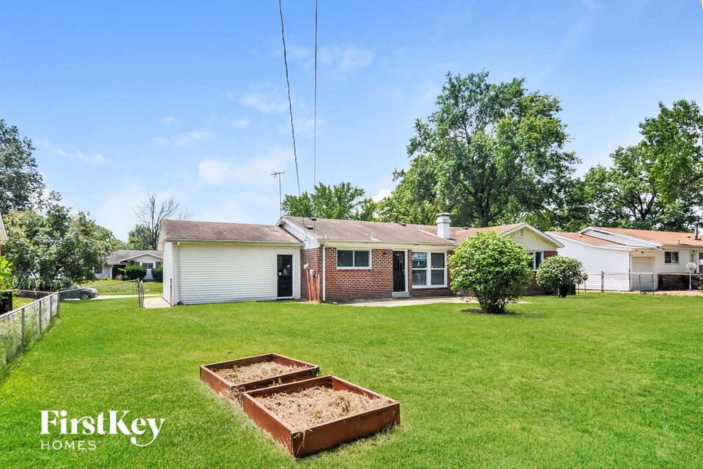 a yard with a house and some raised garden beds