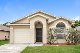 a beige house with a garage door and a lawn
