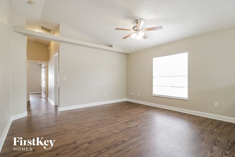 an empty living room with wood flooring and a ceiling fan