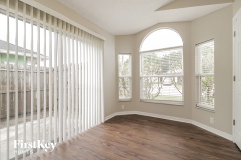 an empty living room with wood floors and a large window