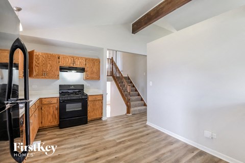 a kitchen with wooden cabinets and a black stove and a staircase