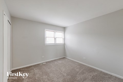 a bedroom with white walls and carpet and a window