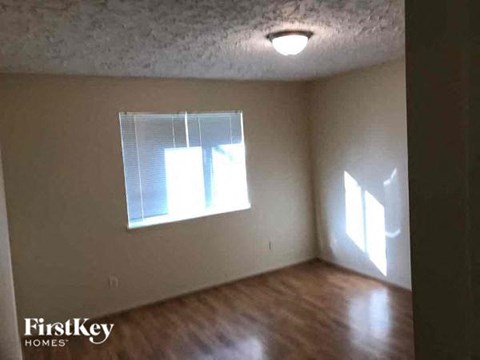 an empty room with a window and wood floors