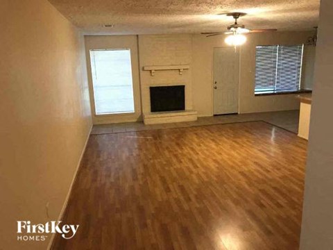 an empty living room with a wood floor and a fireplace