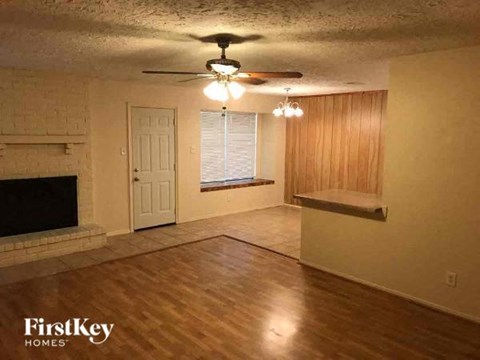 an empty living room with a fireplace and a ceiling fan