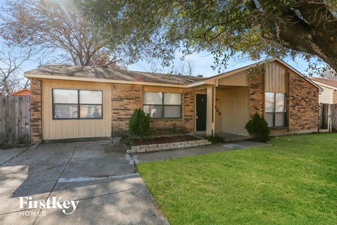 a small brick house with a driveway and a tree