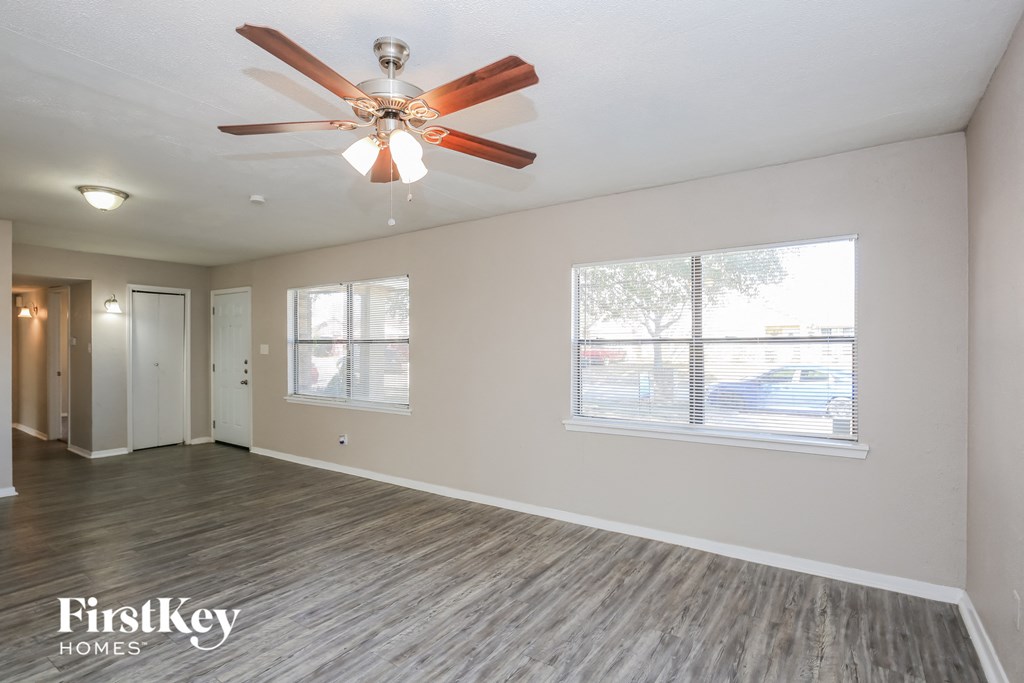 the living room of an empty house with a ceiling fan